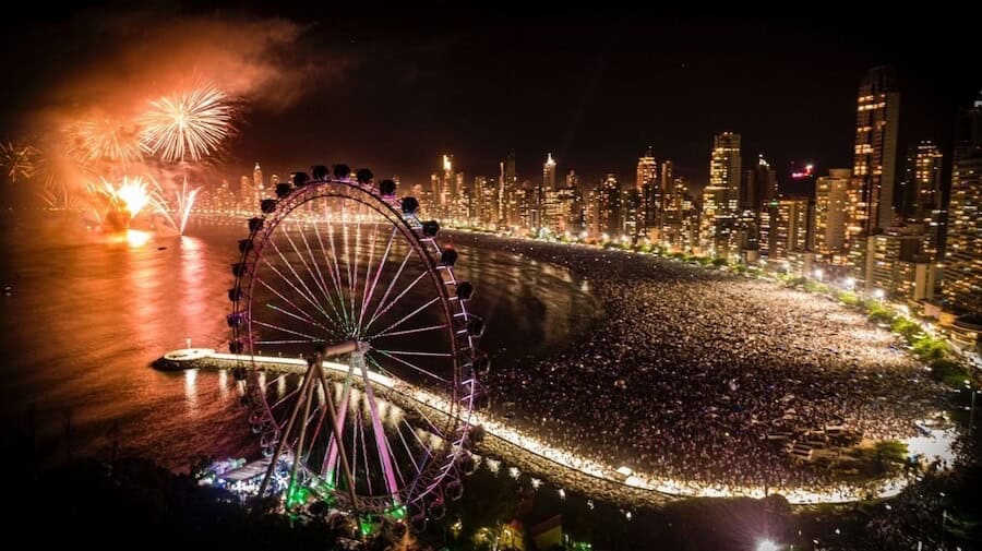 Espectáculo de fuegos artificiales en balneario camboriu con vista a la rueda gigante y paisaje urbano.