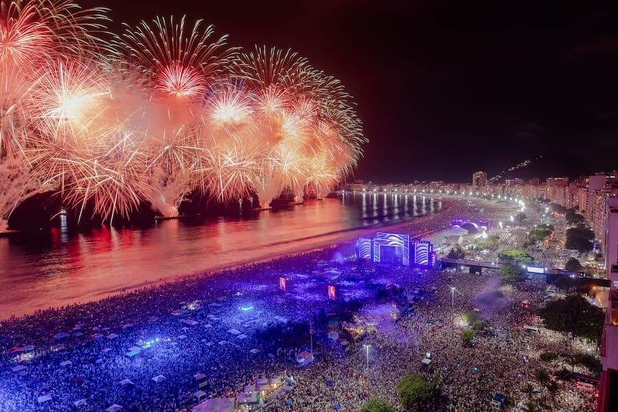 Vibrante vista nocturna de Copacabana, Rio de Janeiro, con fuegos artificiales y multicolor luces en el centro urbano.